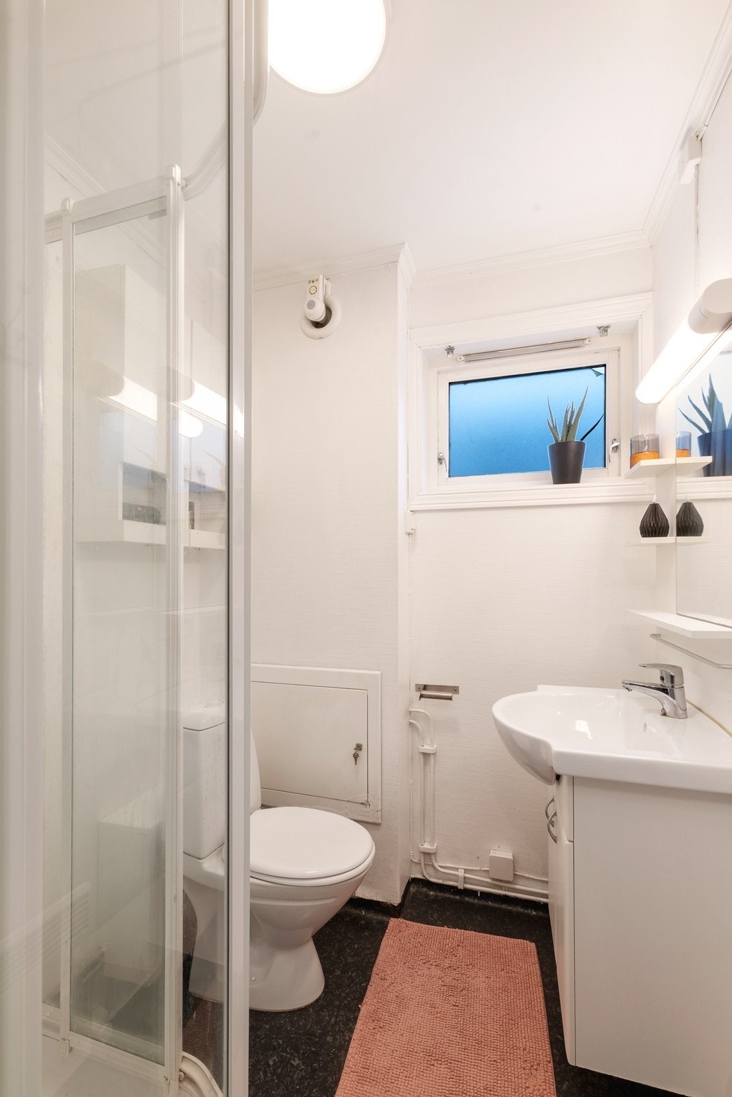 Bad med belegg på gulv. Badet har dusjkabinett, servant og toalett. Galleribilde