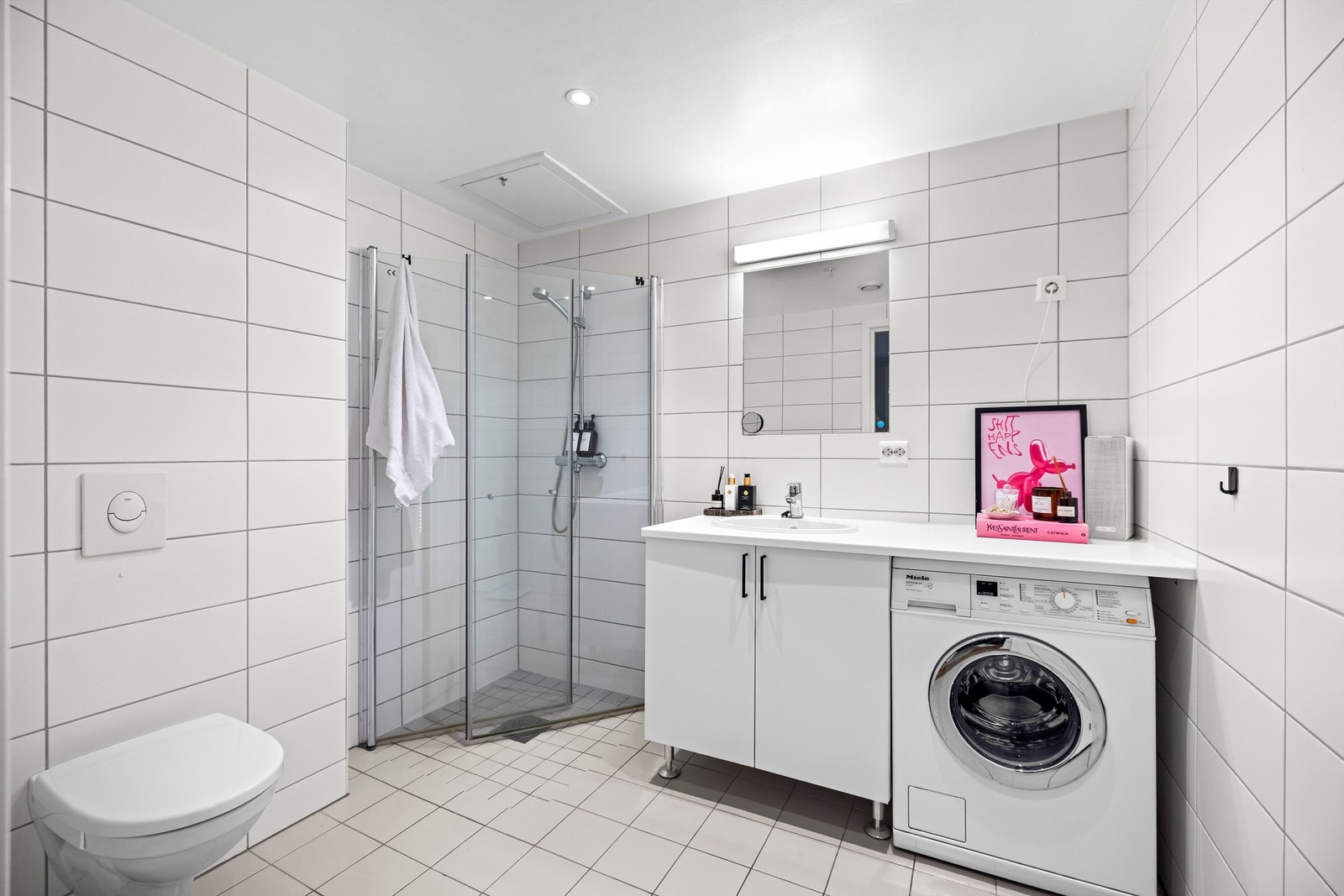 Bad fra 2018 med flislagte overflater og varmekabler i gulv, vegghengt toalett og opplegg for vaskemaskin. Galleribilde