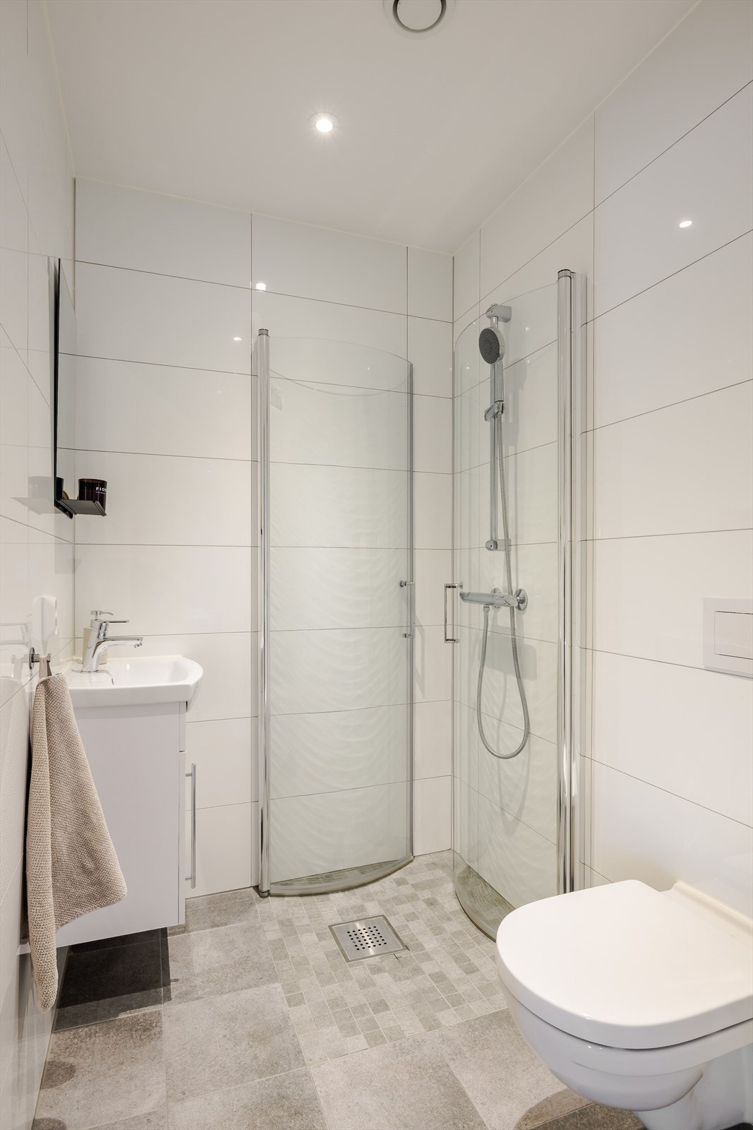 Lyst og moderne baderom 2 i boligens 1. etasje. Baderommet fra 2020 har moderne fliser på gulv og vegger, elektrisk gulvvarme, downlights i himlingen og avtrekk via balansert ventilasjon. Galleribilde