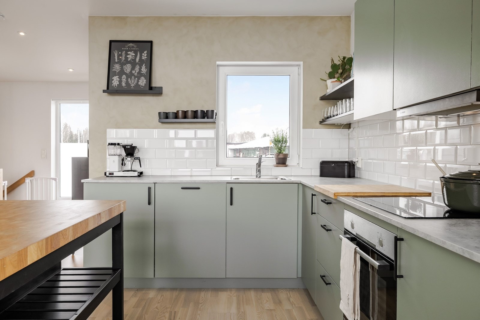 Lys benkeplate av laminat me nedfelt oppvaskkum. Både fint og praktisk med lekre fliser i benkeryggen og vegghengte hyller for oppbevaring og dekor. Galleribilde