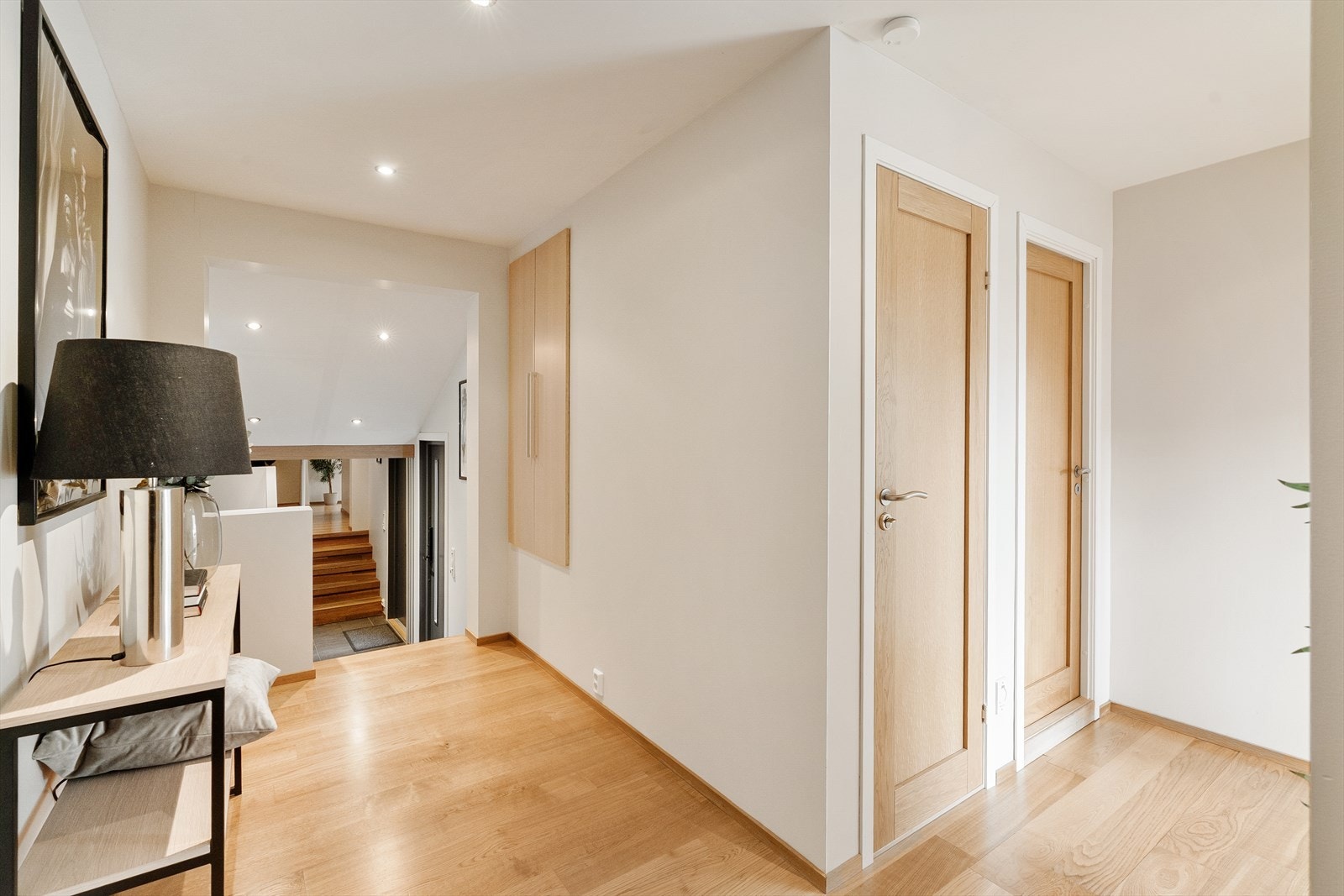 Gang med en-stavs eikeparkett på gulv, malte vegger og spotter i tak. Galleribilde