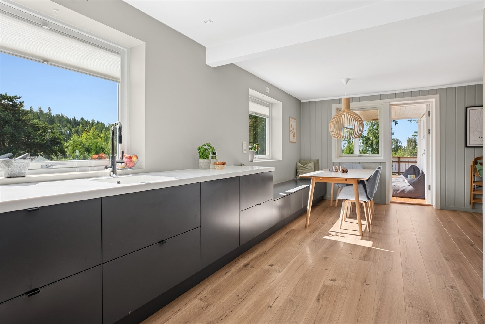 Kjøkkenet har en moderne, glatt innredning i tidsriktige farger, kombinert med stilrene, hvite benkeplater. Galleribilde