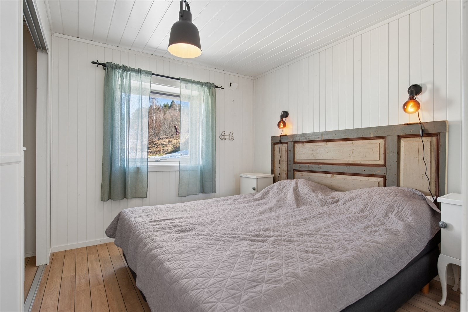 Soverom i første etasje med panel på vegger og plass til dobbeltseng. Galleribilde