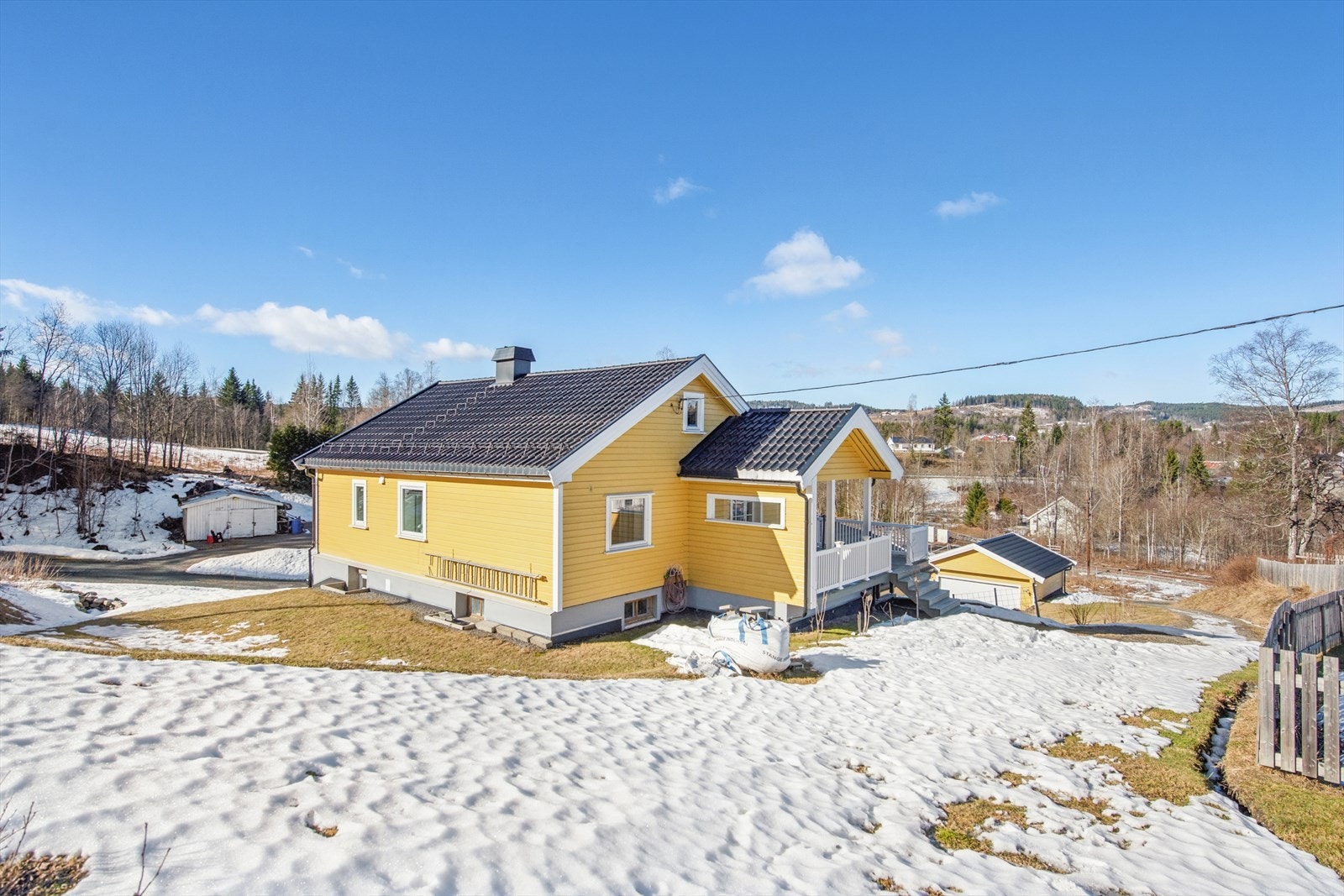 Eiendommen ligger på en skrånende tomt som er opparbeidet med plen og gruset gårdsplass. Galleribilde