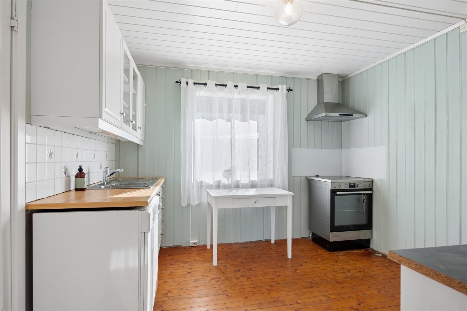 Funksjonelt kjøkken med laminert benkeplate og flislagt sone over arbeidsflaten. Plass for frittstående hvitevarer. Galleribilde