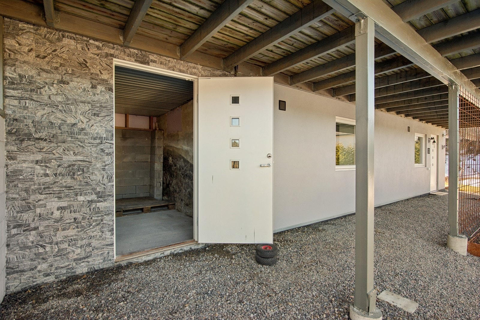 Gruset uteplass foran inngangen til kjelleren. Her er det også en praktisk, utvendig bod. Galleribilde