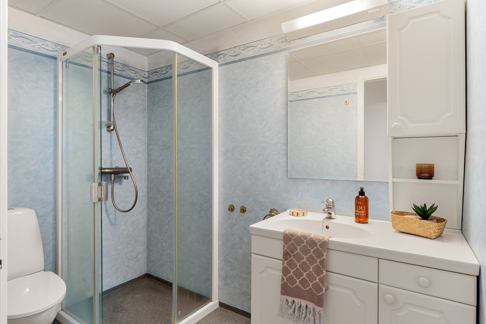 Badet er utstyrt med servant i innredning, toalett og dusjkabinett. Galleribilde