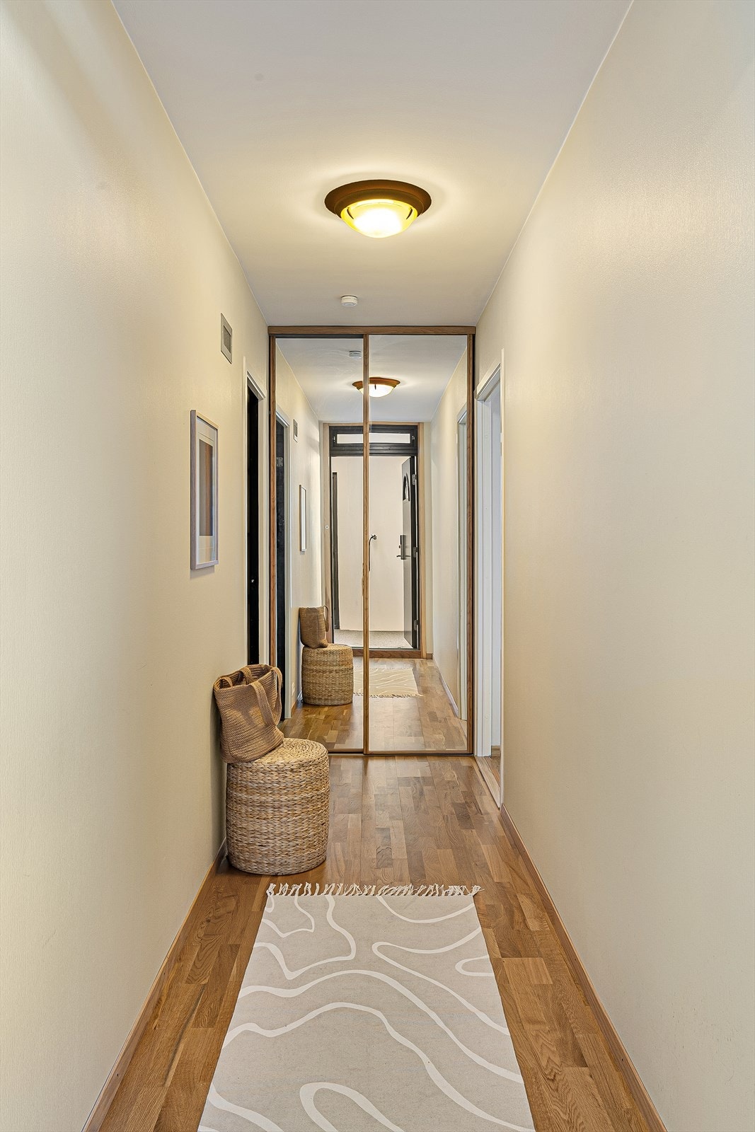 En romslig skyvedørsgarderobe med speilfronter i gangen gir rikelig med oppbevaringsplass. Galleribilde