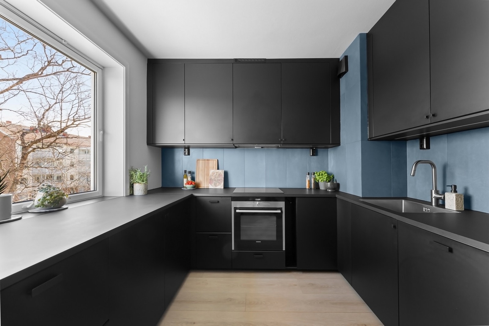 Kjøkkeninnredning fra 2021 med sorte, glatte fronter og sorte laminerte benkeplater Galleribilde