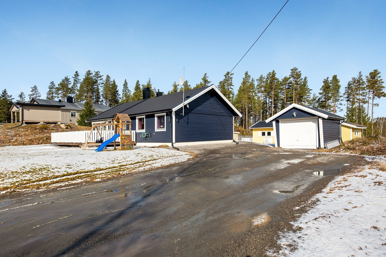 Gruslagt innkjørsel og gårdsplass fører frem til boligen og en frittstående garasje på 15 m². Galleribilde
