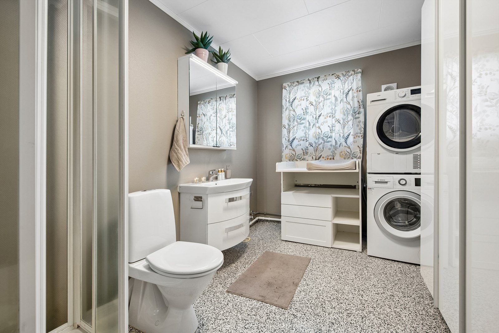 Rommet er et kombinert bad og vaskerom, med praktisk opplegg for vaskemaskin. Galleribilde