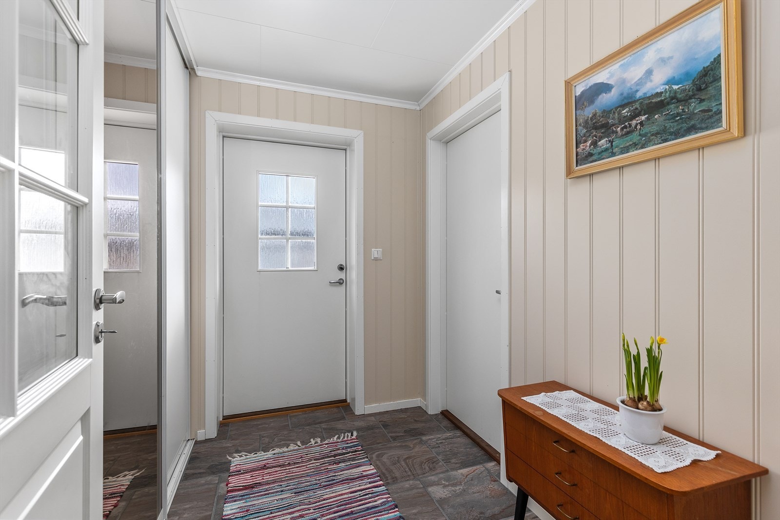Entreen er en del av påbygget fra 2008, praktisk innredet med skyvedørsgarderobe. Døren til høyre er direkte til garasjen. Galleribilde