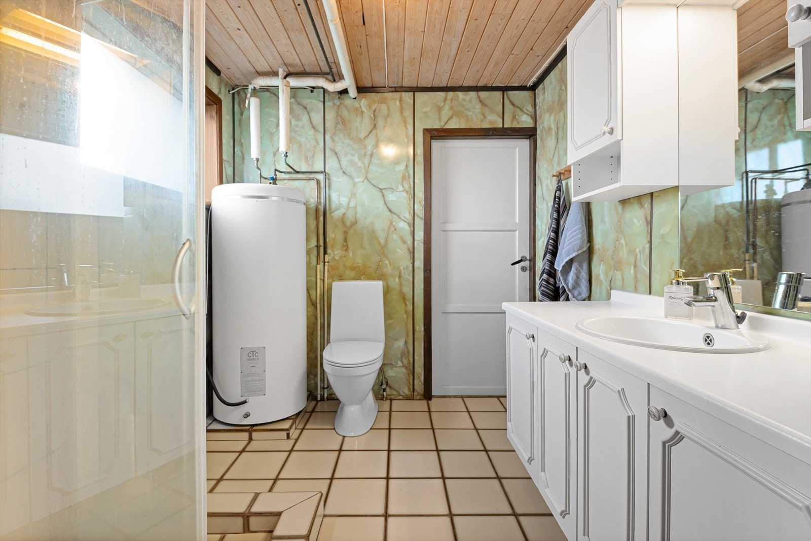 Badet har innredning med servant nedfelt i servantskap, veggskap, speil, toalett og dusj Galleribilde