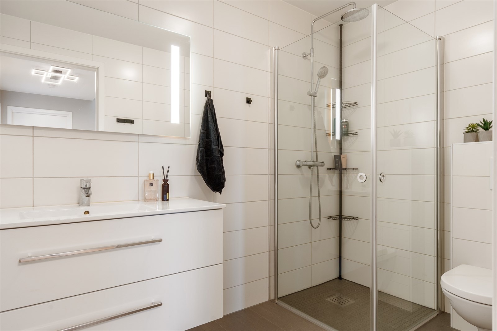 I boligens 1. etasje finner du et tidløst og pent bad med fliser på gulv og vegger - det er varme i gulvet som bidrar til en behagelig romtemperatur Galleribilde