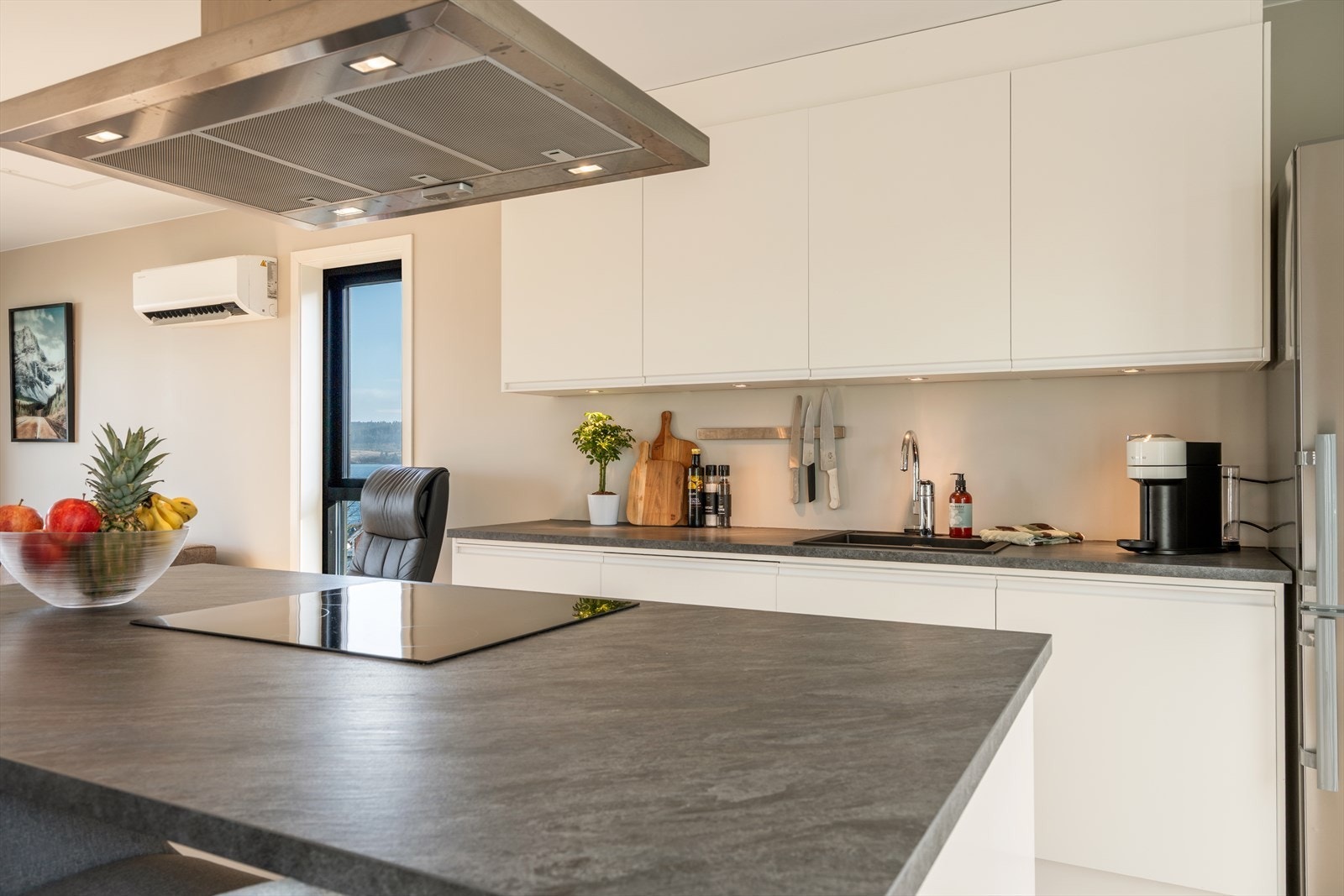 Kjøkkenet har slette fronter og laminat benkeplate - videre er det integrert platetopp, komfyr og oppvaskmaskin, samt frittstående kjøl/fryseskap Galleribilde