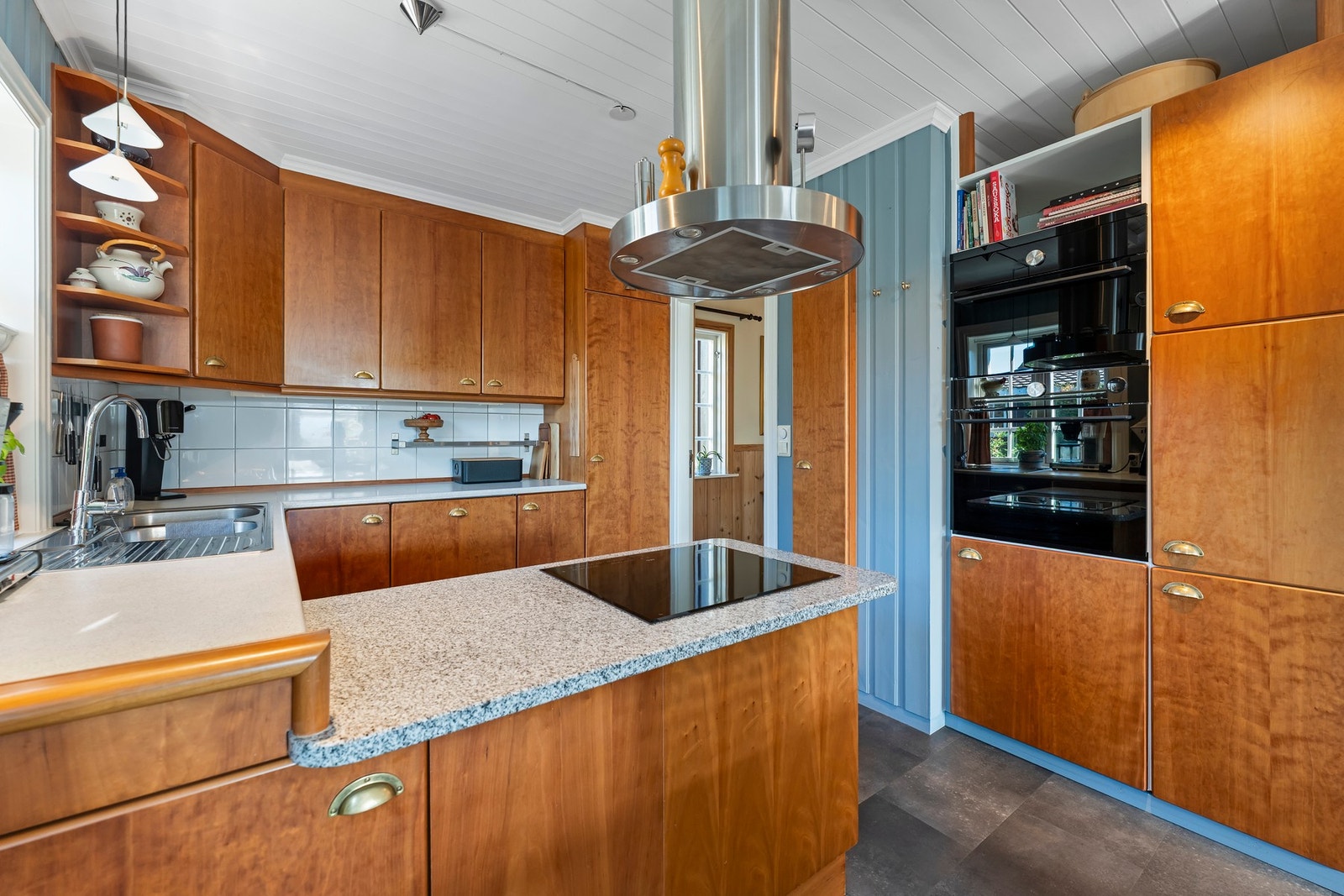 Flott kjøkken med integrert stekeovn, kombiovn, koketopp, oppvaskmaskin, kjøleskap. Benkeplate i sten. Galleribilde