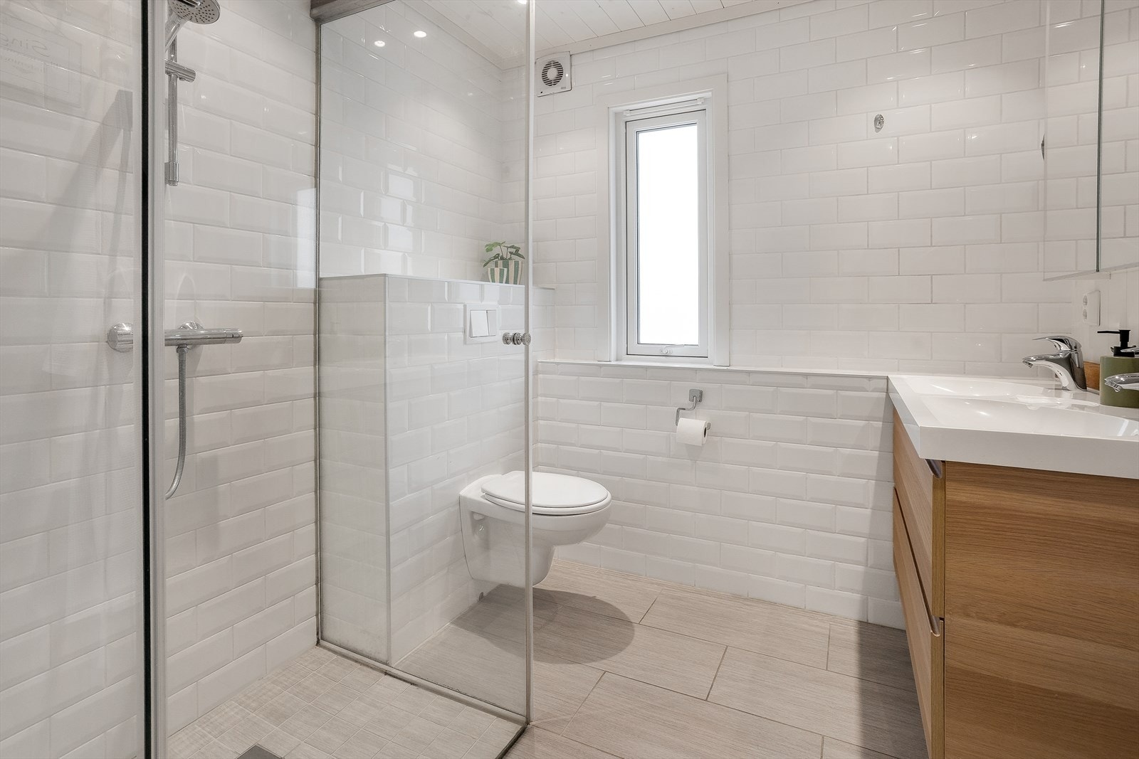 Badet er innredet med praktisk baderomsinnredning med dobbel servant, dusjhjørne og veggmontert toalett. Galleribilde