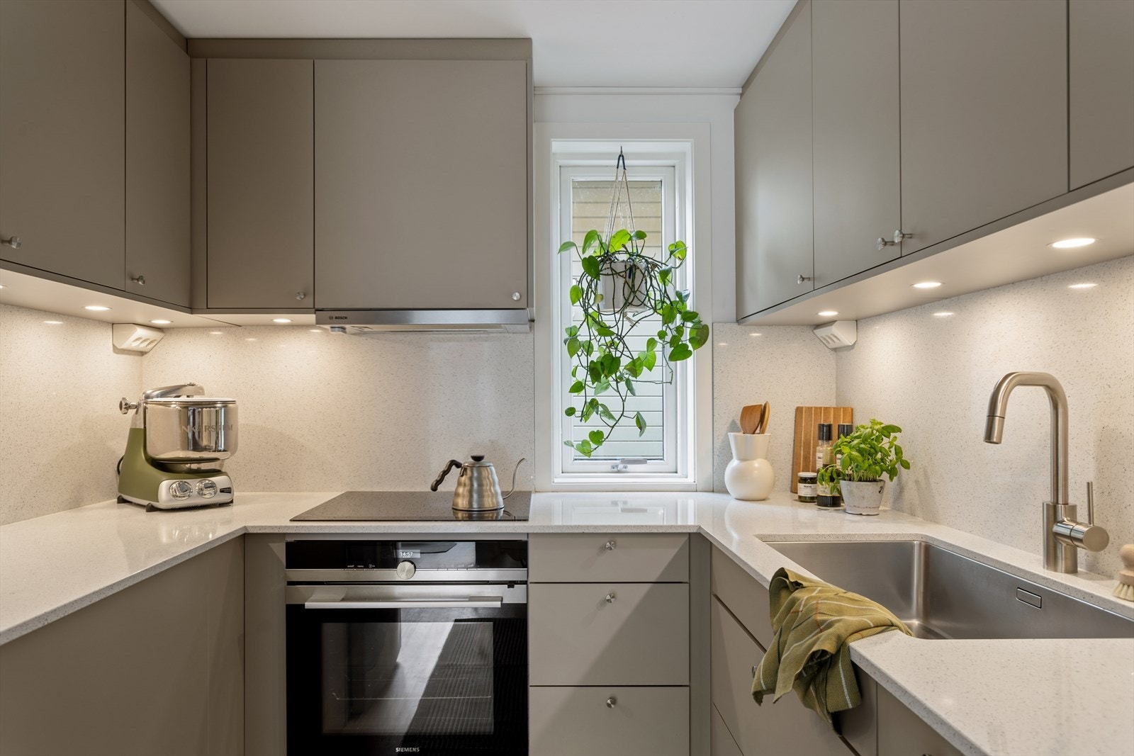 Kjøkkenet har en moderne innredning fra 2021 med glatte fronter i en elegant mocca-farge. Kjøkkenet har vindu over benken som gir rikelig med naturlig lys til matlagingen. Galleribilde