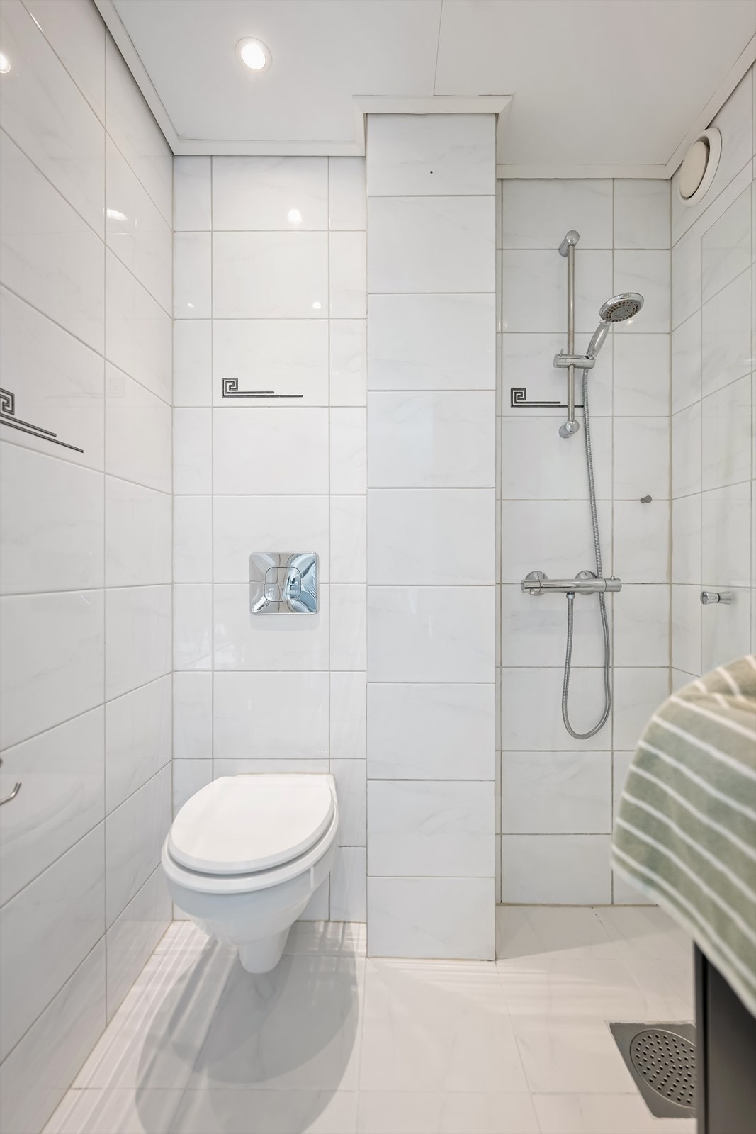 Rommet er utstyrt med veggmontert toalett og et funksjonelt dusjhjørne med rett, svingbar dusjdør. Dusjen har termostatstyrt batteri. Galleribilde