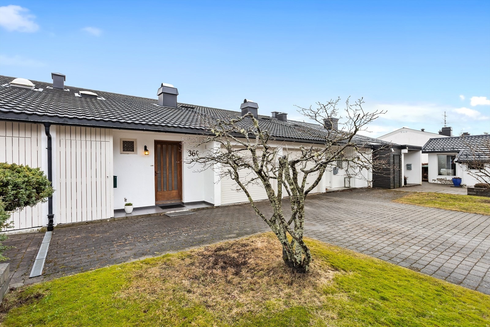 Tomten har gårdsplass med belegningsstein. Integrert garasje ved inngangspartiet. Galleribilde