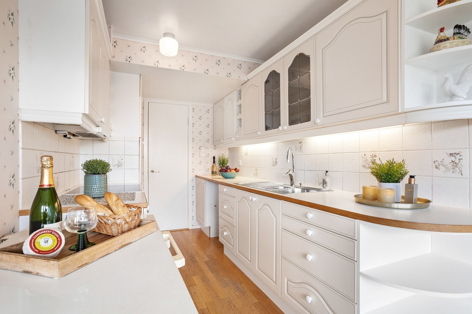 Velholdt og klassisk kjøkkeninnredning med hvite profilerte fronter og benkeplate av laminat med heltre kant. Galleribilde