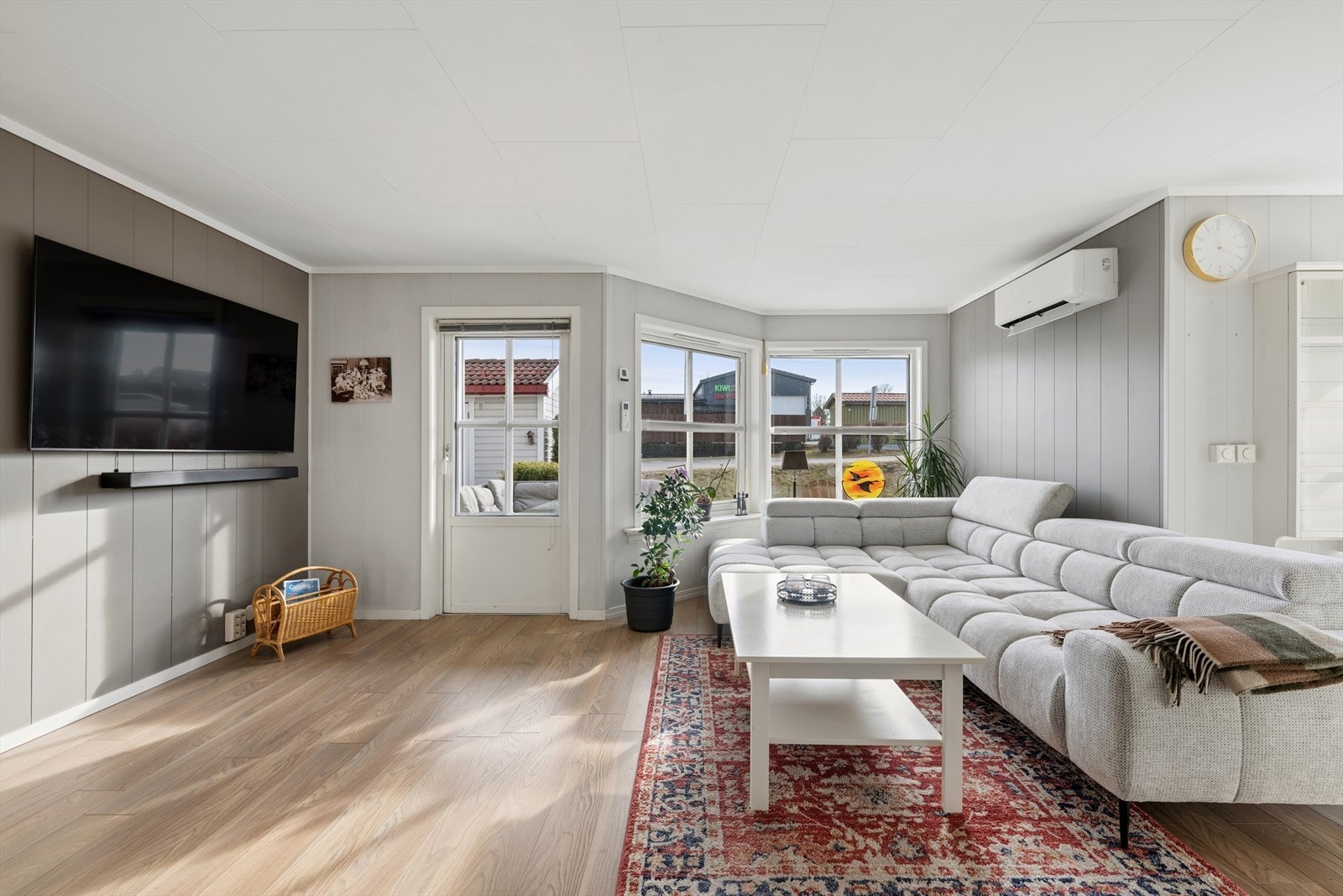 Store vindusflater gir godt med naturlig lys til stuen, som har laminatgulv og malte veggplater. Galleribilde