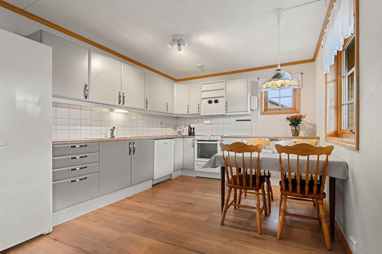 Lyst og fint kjøkken med utsparing for kjøl/fryseskap, oppvaskmaskin og komfyr. Galleribilde