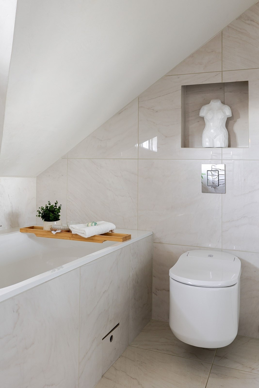 Innmurt badekar under vinduet. Baderommet er også utstyrt med dusjhjørne med glassdører og både hånd- og regnfallsdusj, samt vegghengt toalett. Galleribilde