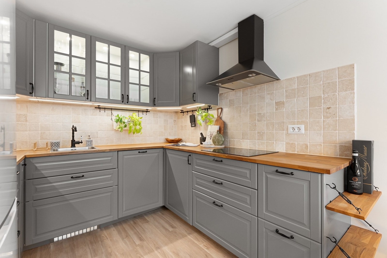 Delikat kjøkken med profilerte fronter på skap og skuffer, benkeplate av tre med kjøkkenvask og veggfliser mellom benkeplate og overskap Galleribilde