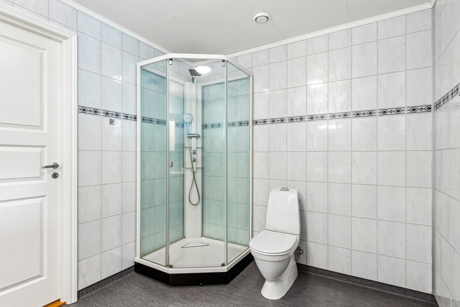 Rommet har våtromsbelegg på gulv, våtromsplater på veggene og er utstyrt med dusjkabinett. Galleribilde