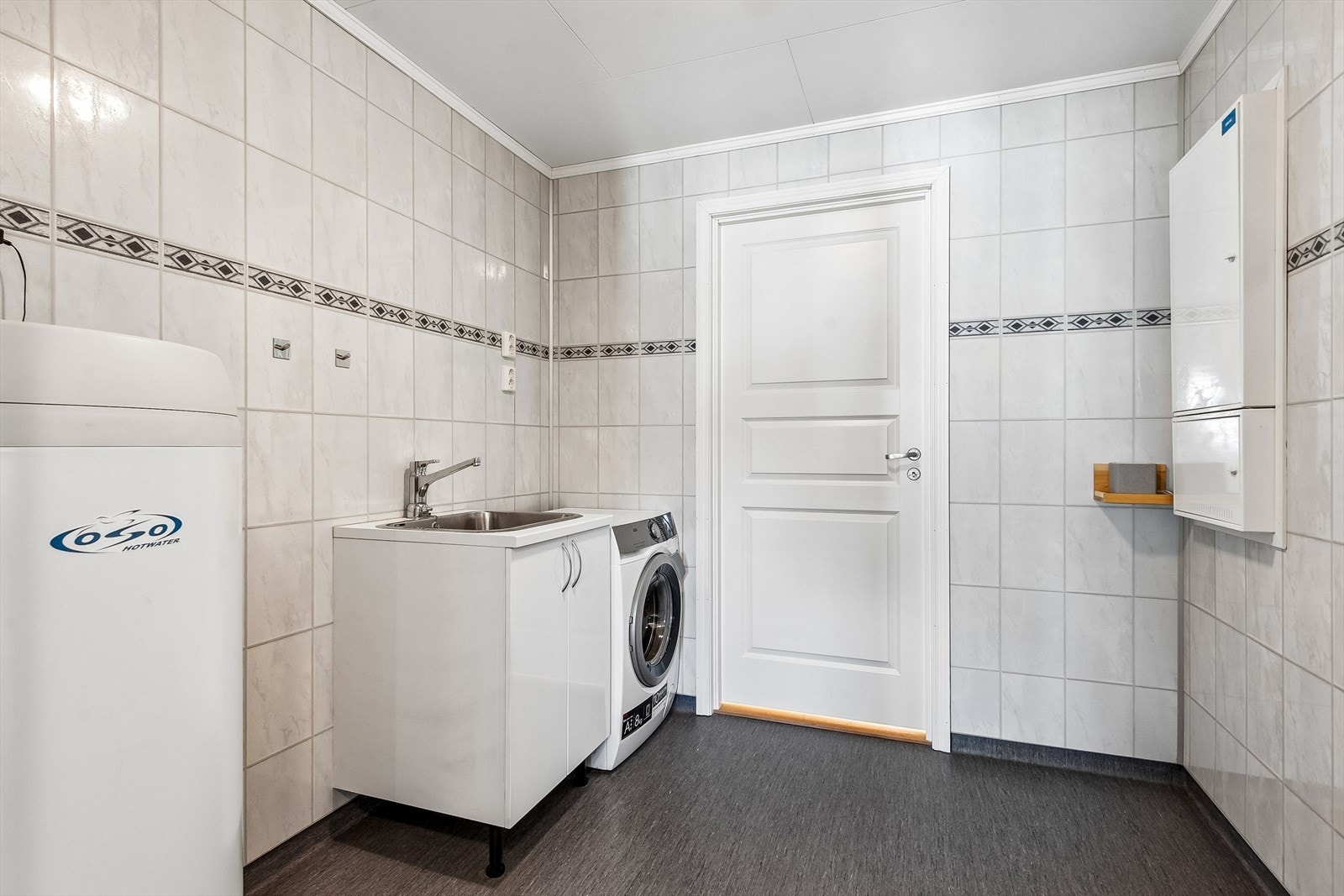 Separat vaskerom med innredning, vaskekum og opplegg for vaskemaskin. Varmtvannstanken er fra 2014. Galleribilde