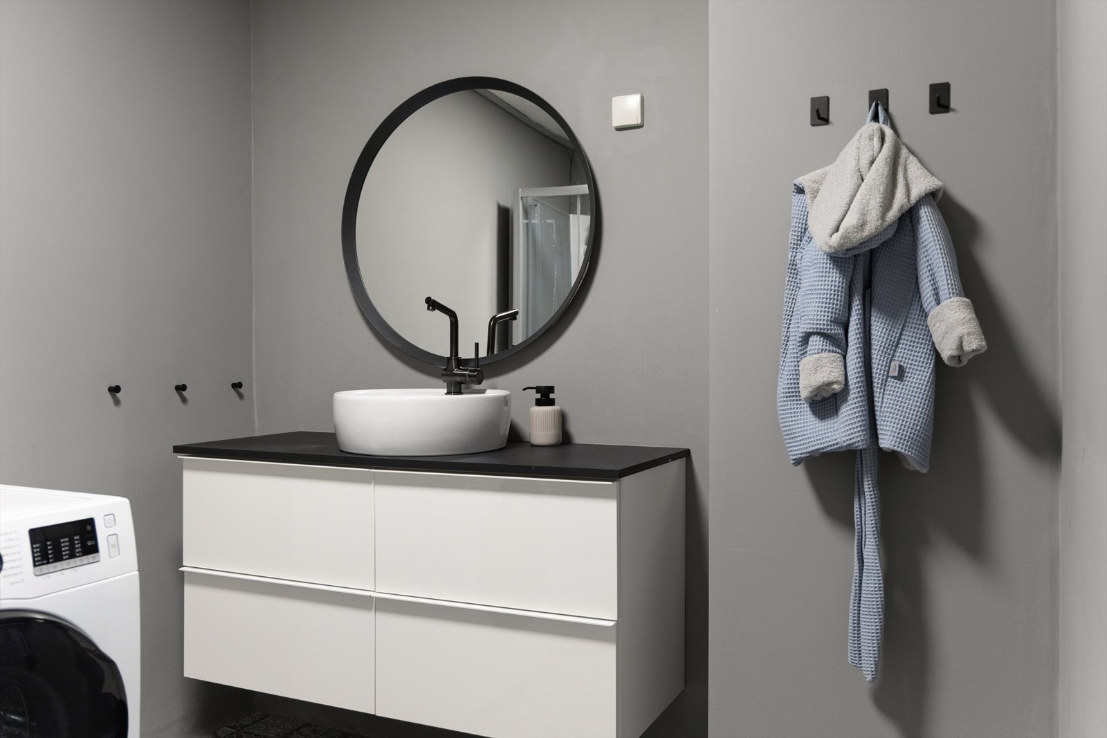 Badet er ellers utstyrt med dusjkabinett og baderomsinnredning med god lagringsplass og servant. I tillegg er det opplegg for vaskemaskin. Sorte detaljer er gjennomgående, noe som gir et moderne uttrykk. Galleribilde