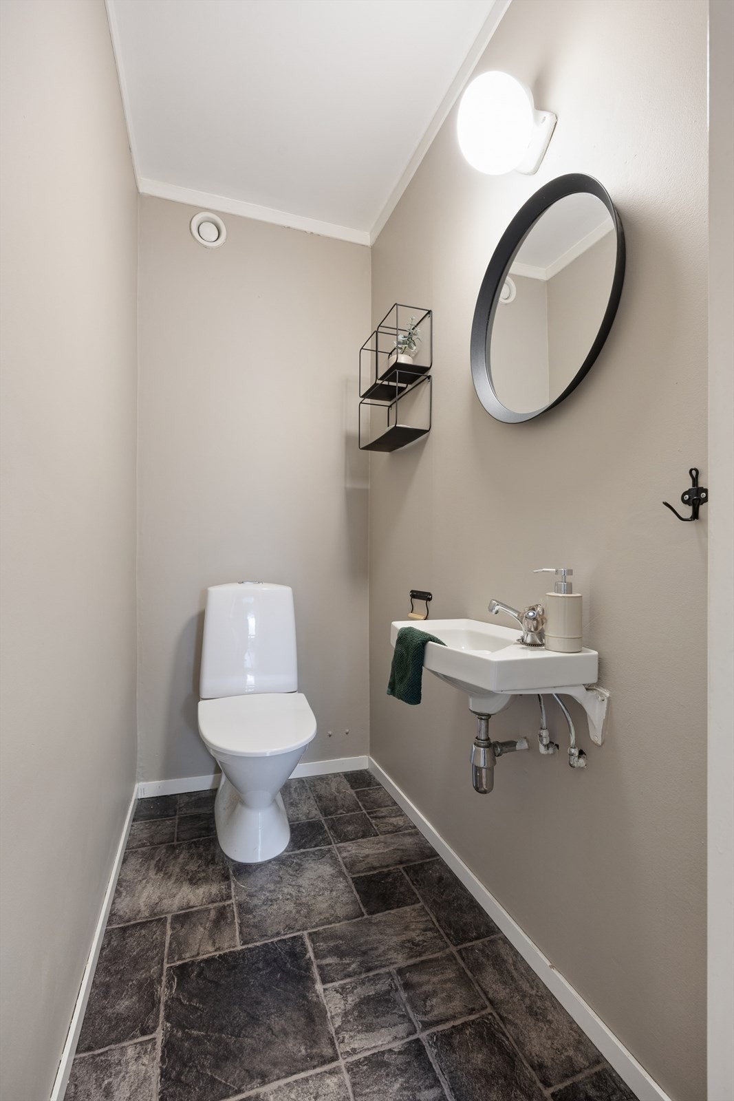 Like ved baderommet finner man et toalettrom som er innredet med belegg på gulv og malte veggflater. Rommet er ellers utstyrt med toalett og servant. Galleribilde