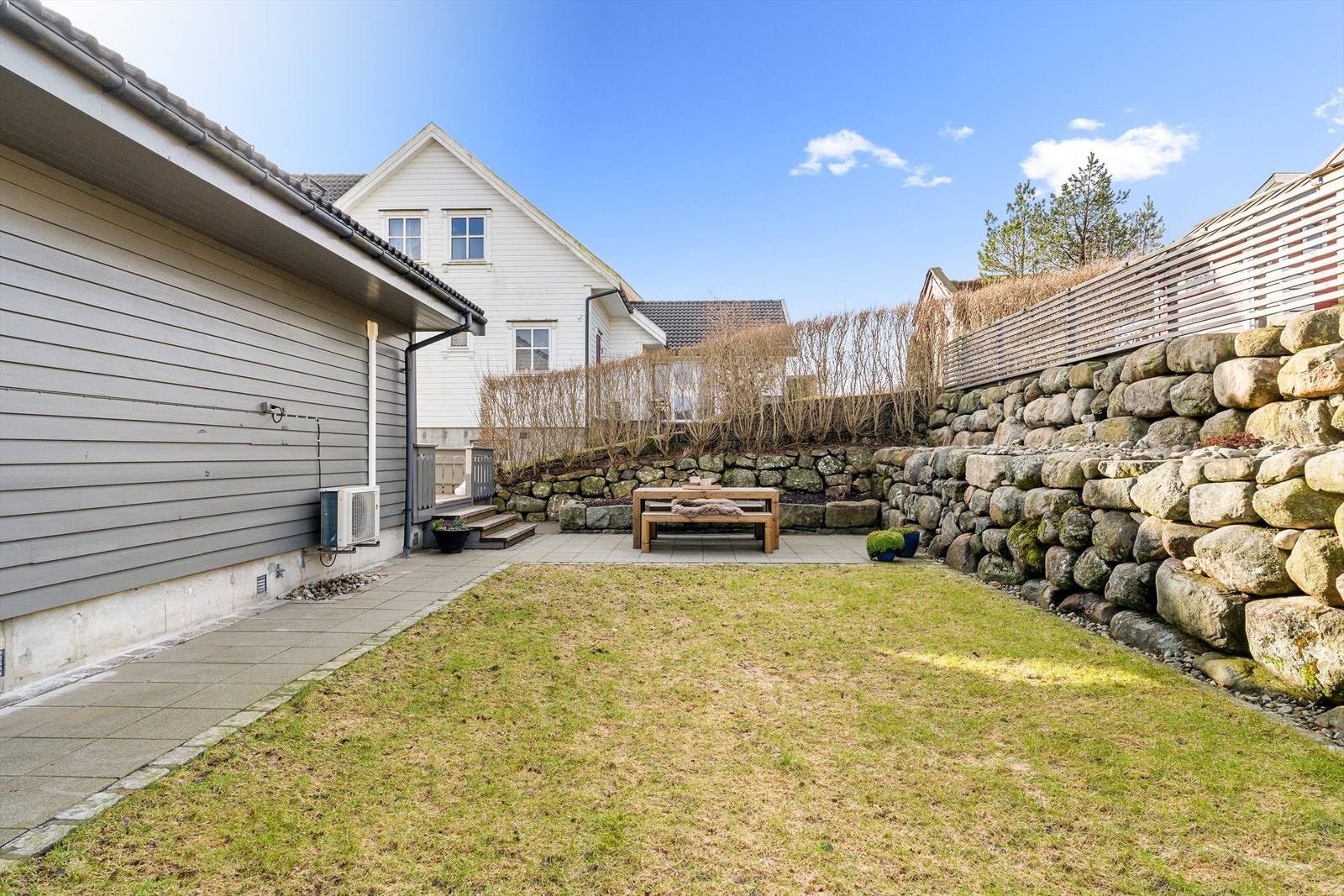 Skjermet og lun hage med gressplen og flere sittegrupper Galleribilde