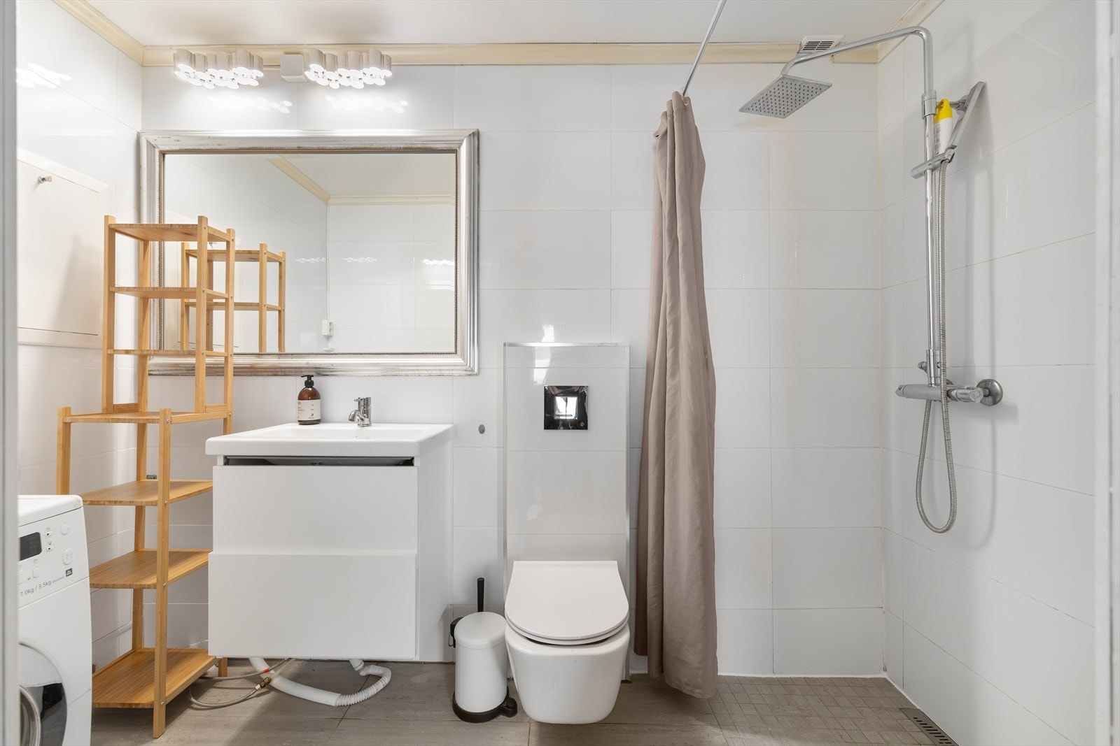 Badet er utstyrt med veggmontert WC, dusjsone med forheng, servant med ettgreps blandebatteri integrert i innredning, samt opplegg for vaskemaskin. Galleribilde