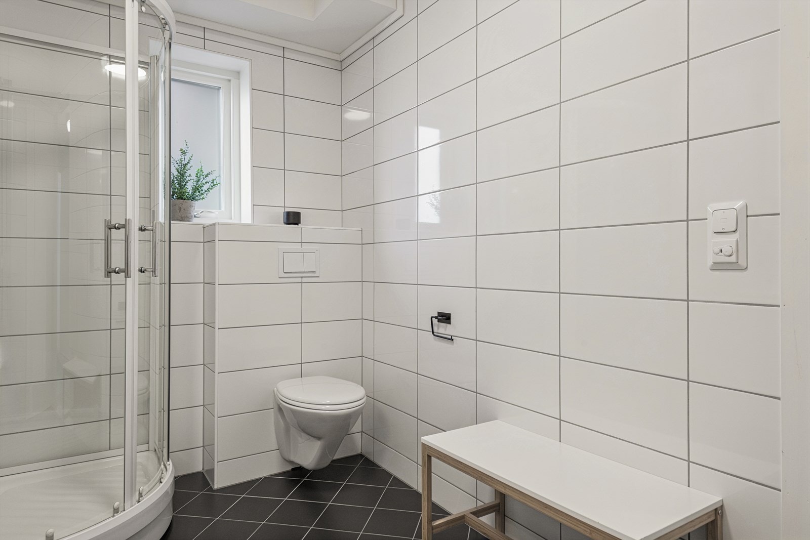 Badet er utstyrt med dusjkabinett og vegghengt toalett. Galleribilde