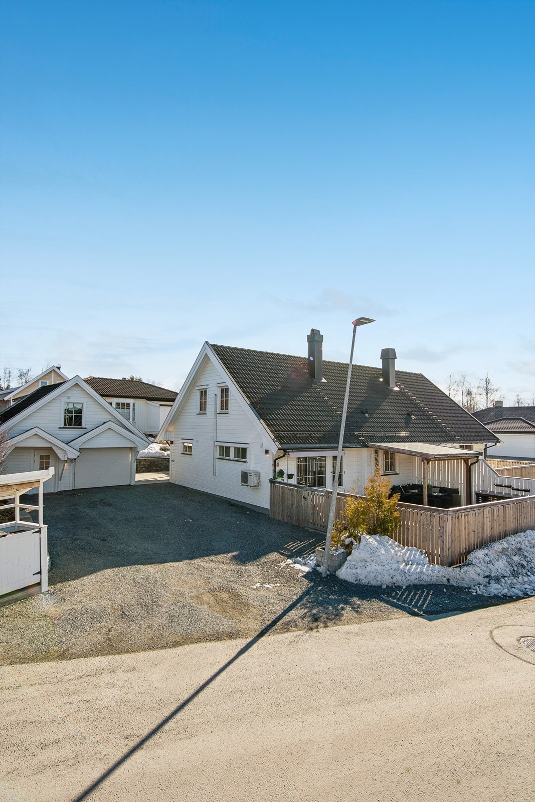 En velholdt vertikaldelt tomannsbolig fra 1994, med garasje og en flat, gruset gårdsplass. Galleribilde