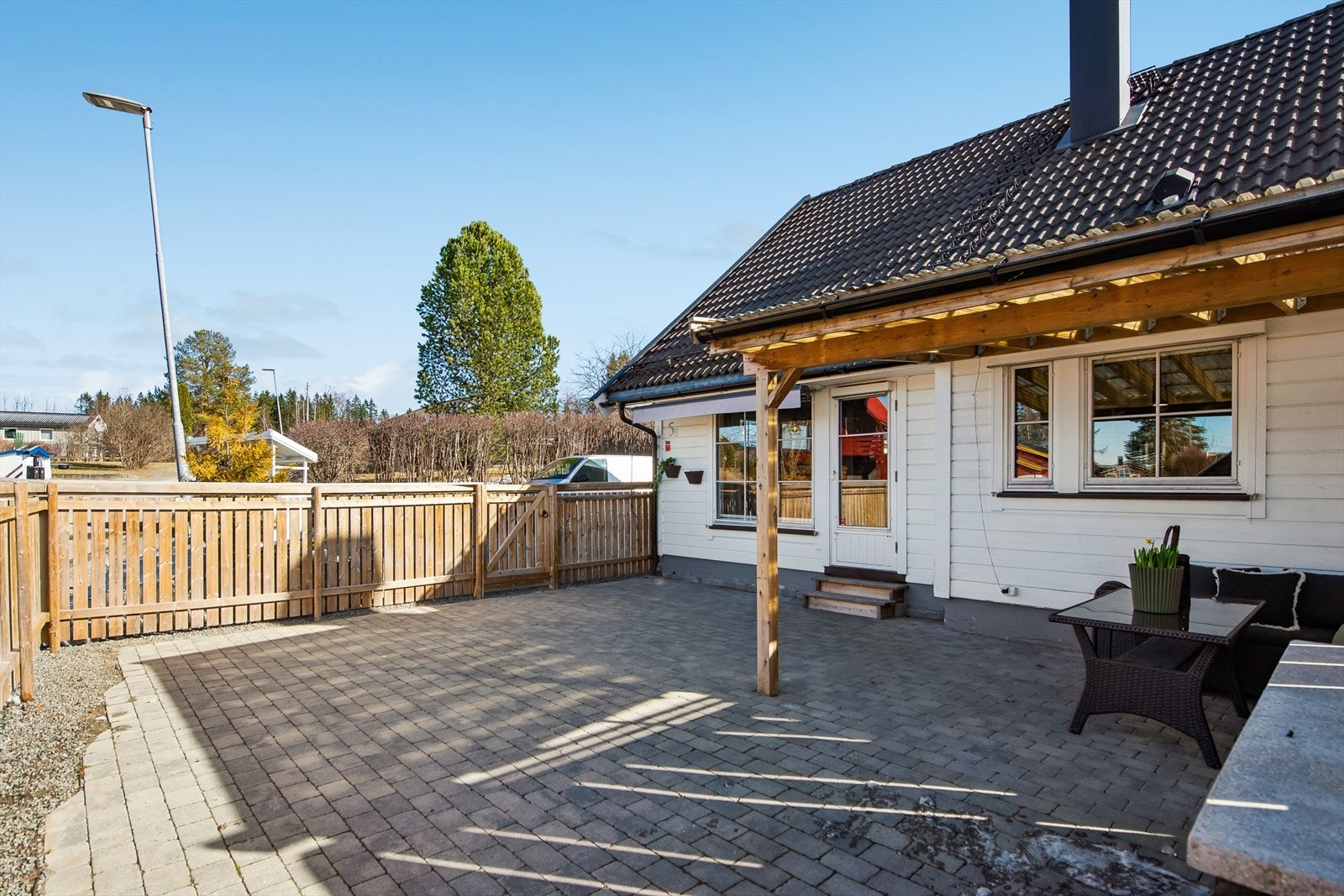 Boligen har to uteplasser. Her er den nordvestvendte med adkomst fra stuen, anlagt med belegningsstein i 2021. Galleribilde