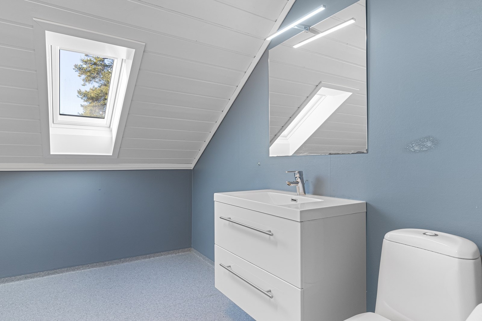 Badet i 2. etasje har belegg på gulv og baderomsplater kombinert med malt strie på veggene. Badet har en moderne innredning med dype skuffer og heldekkende servant, samt speil med overlys. Galleribilde