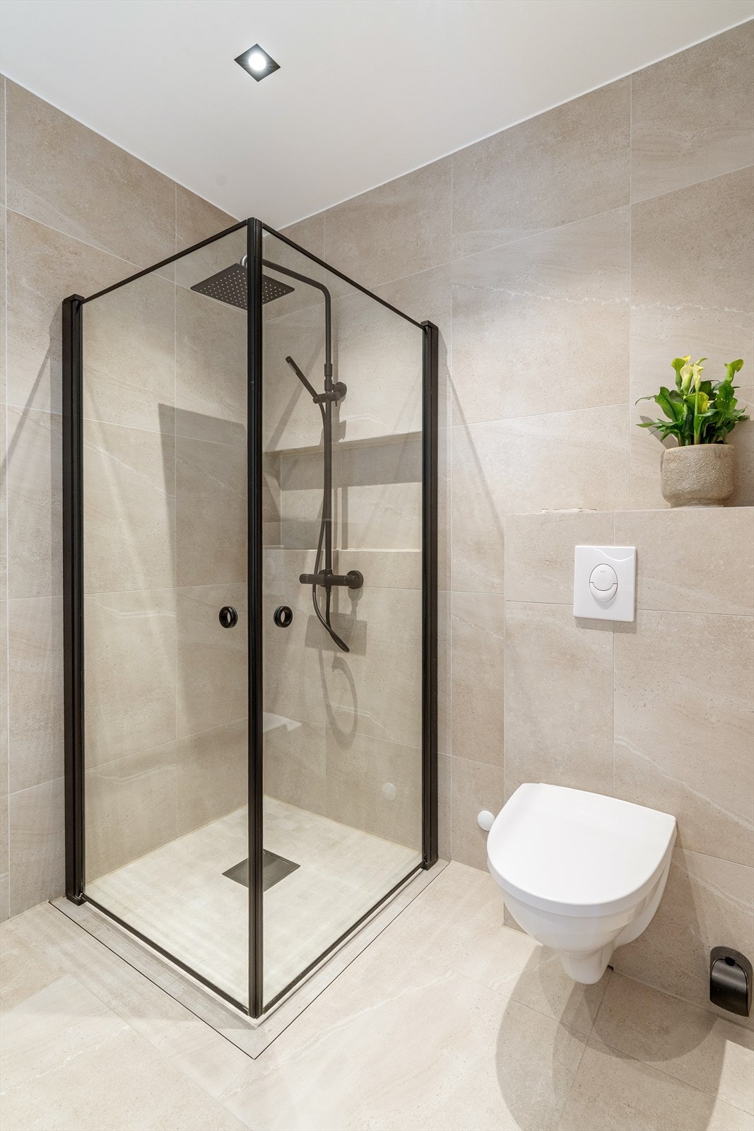 Sorte detaljer på dusj og baderomsinnredning passer fint med filsene som har en sandfarge. Galleribilde