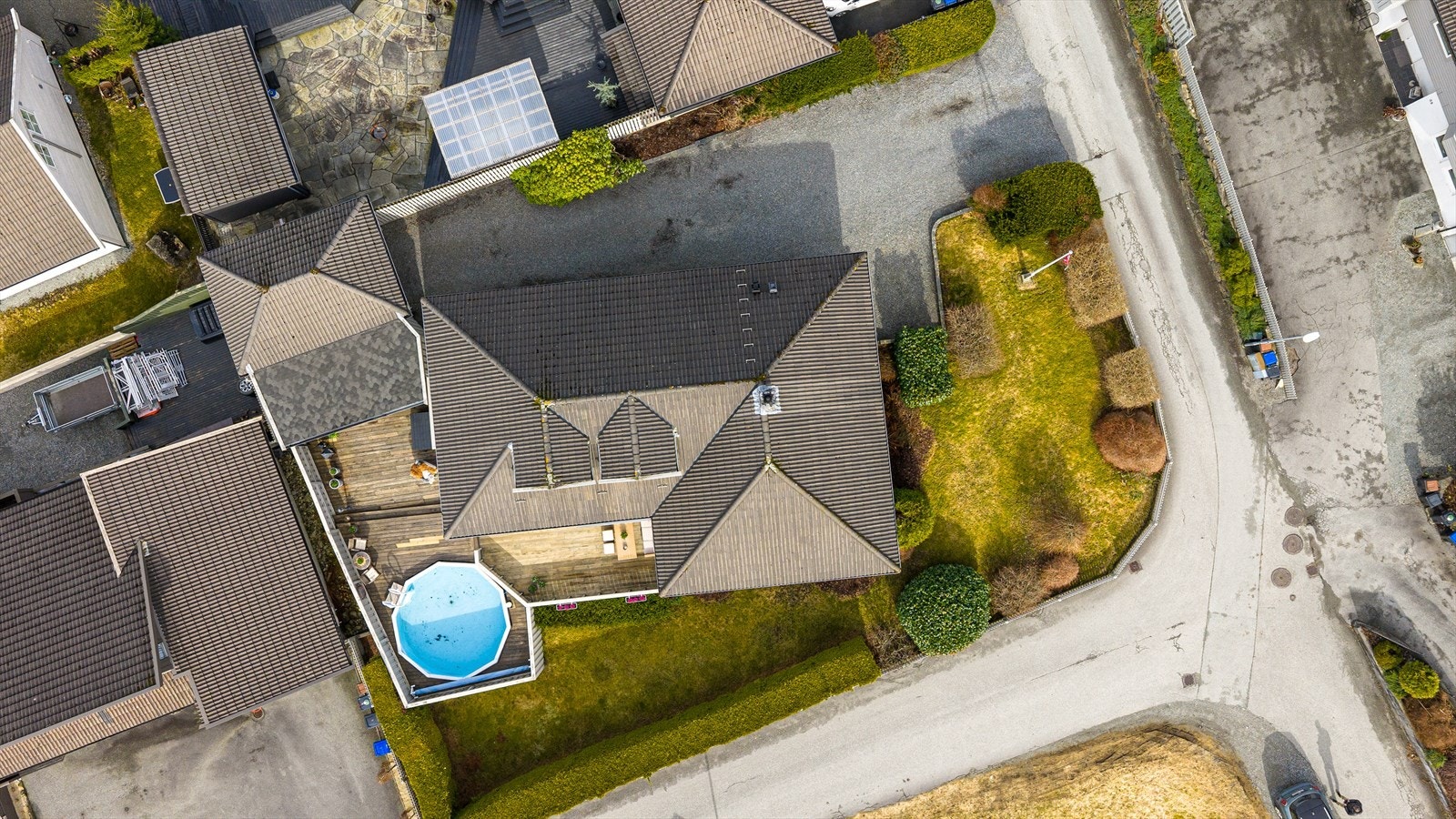 Tomten er pent opparbeidet med store terrasser, basseng, singlet gårdsrom, plen, hekker, trær og prydsbusker Galleribilde