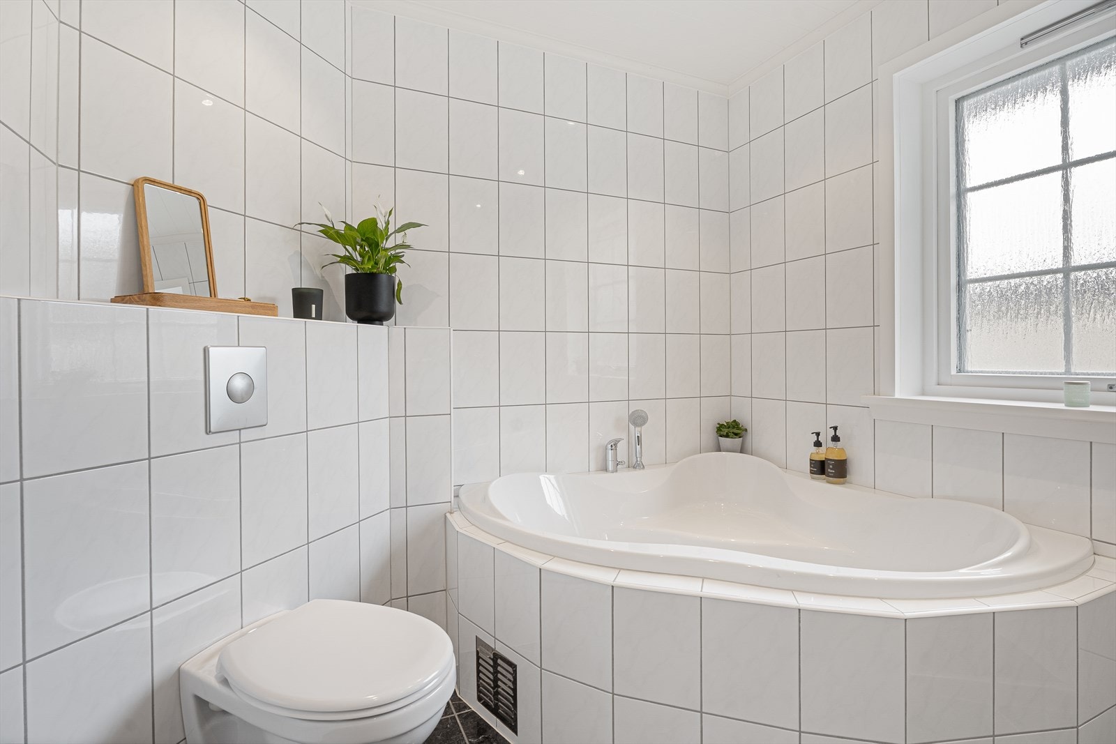 Badet er innredet med dobbel servant, vegghengt toalett, badekar og dusjnisje med glassdører Galleribilde