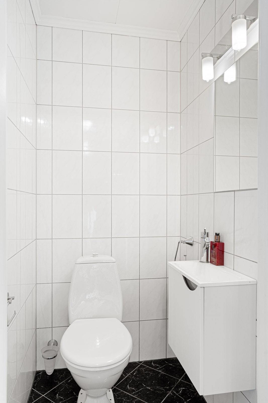 Pent toalettrom i 1. etasje med fliser på gulv og vegger samt malte plater i himlingen Galleribilde