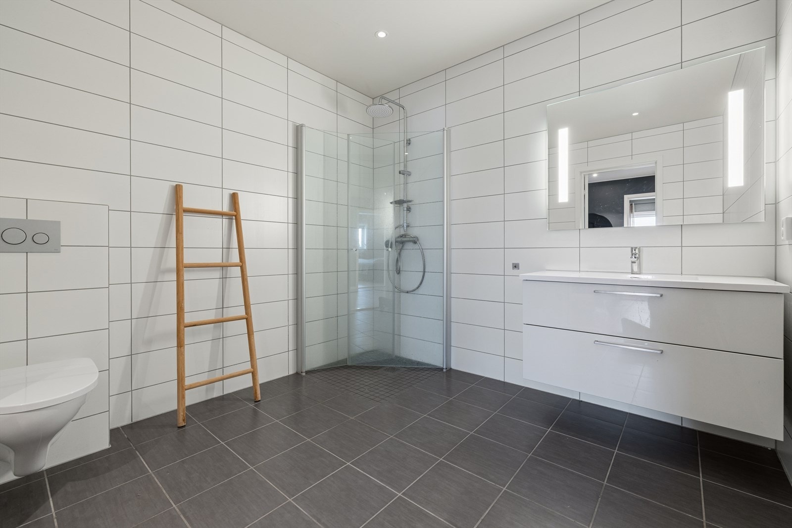 Bad i underetasjen. Badet har innredning med nedfelt servant, veggmontert toalett og dusjvegger/hjørne. Galleribilde