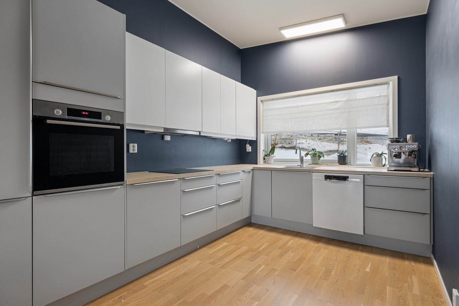 Kjøkkenet har innredning med glatte fronter. Benkeplaten er av laminat. Det er integrert kjøl/fryseskap, oppvaskmaskin, induksjonstopp og stekeovn Galleribilde