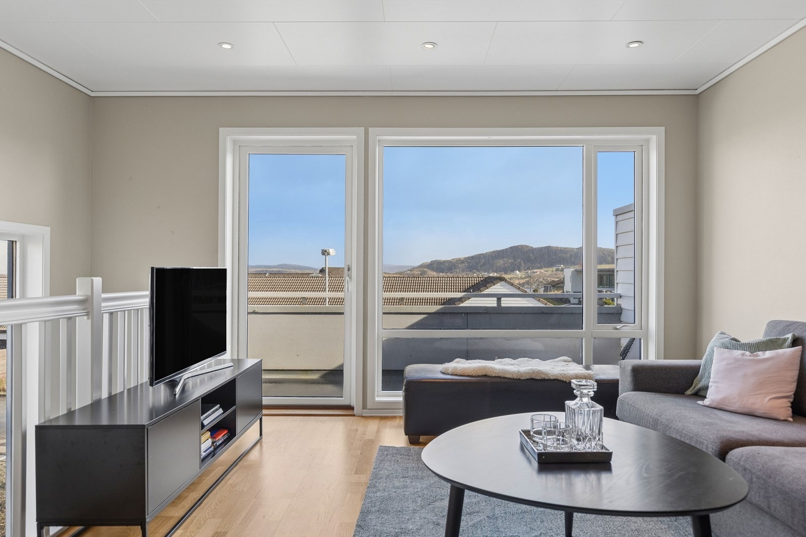 Fra stue og balkong har man flott utsikt over nabolaget og omgivelsene. Her får man også et glimt av sjøen. Galleribilde