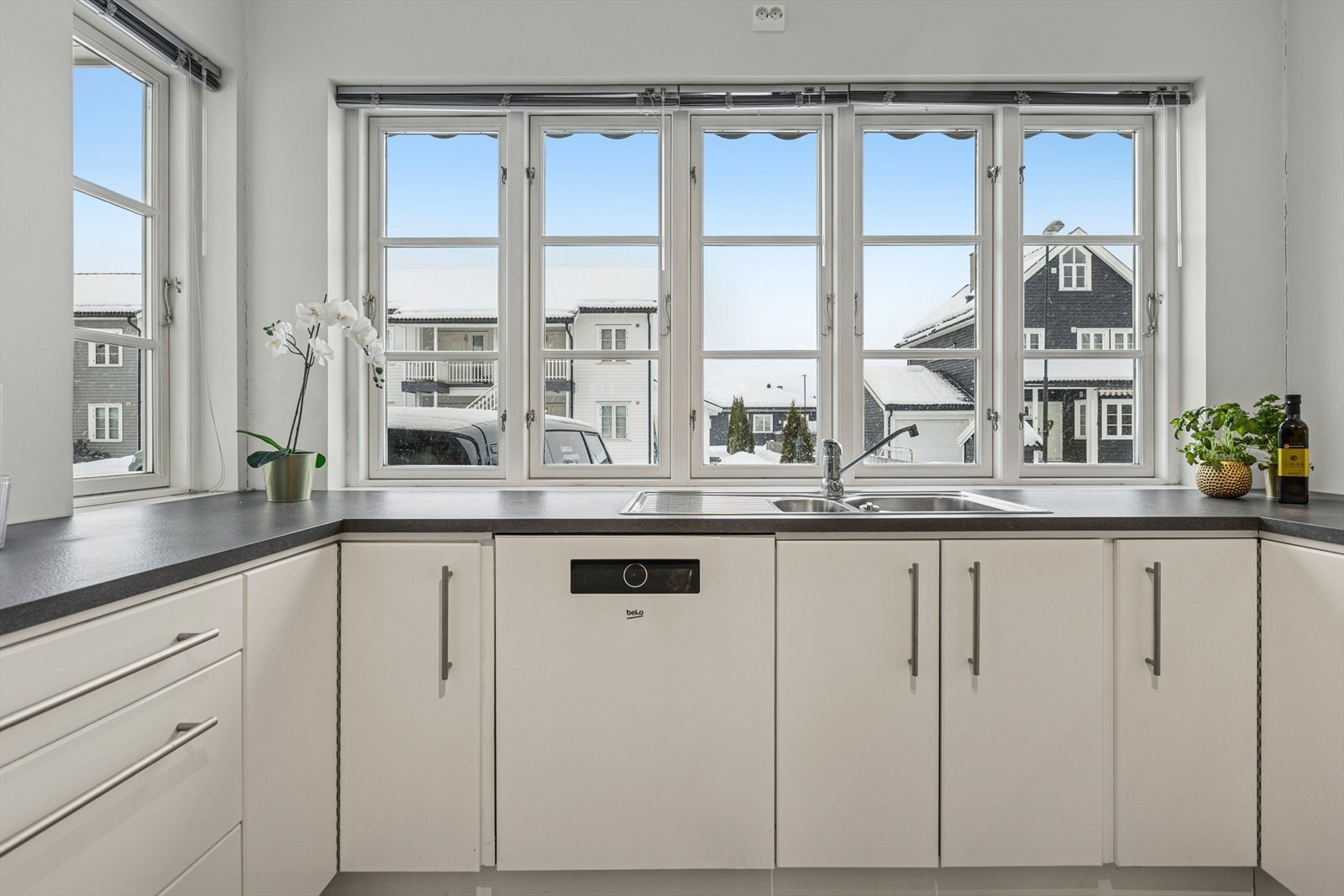 Store vindusflater over kjøkkenbenken gir godt med arbeidslys og utsyn. Galleribilde