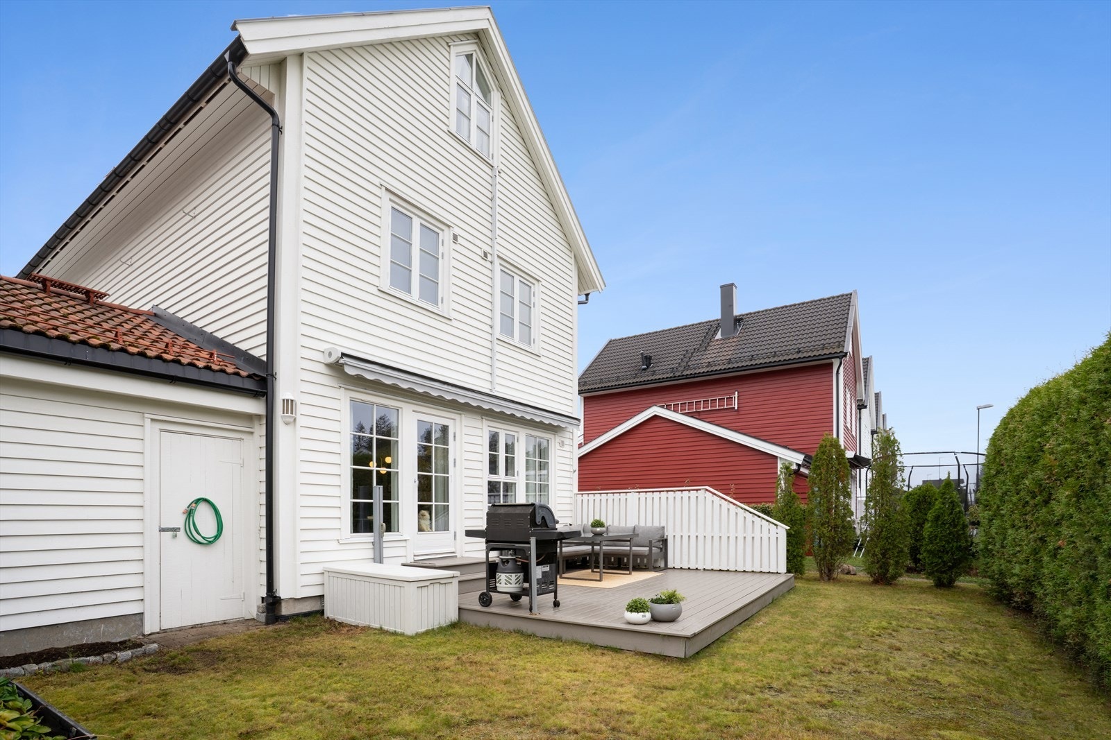 Pen og velstelt hage med plen, hekk og en praktisk utvendig bod. Galleribilde