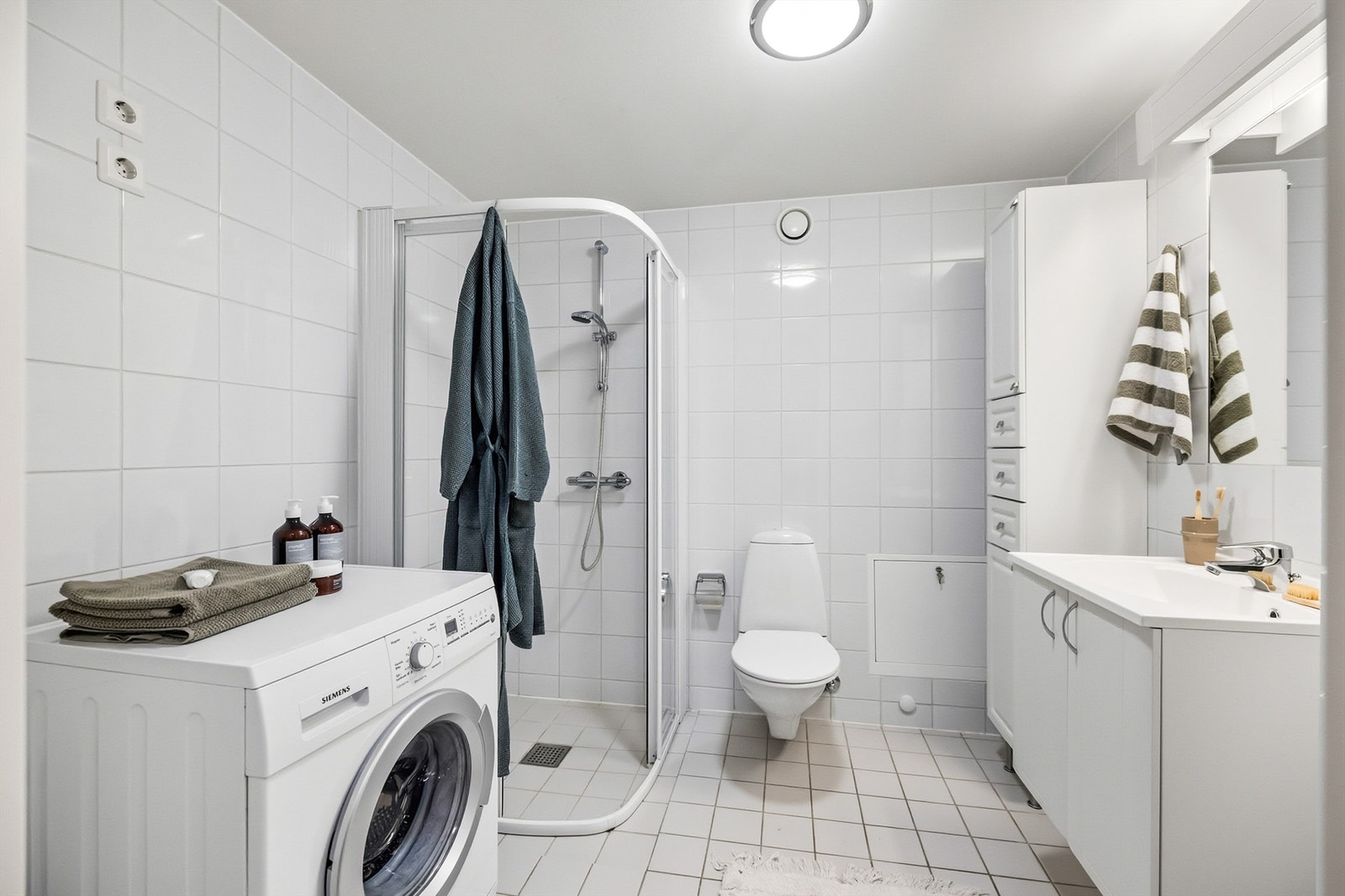 Baderommet er fra byggeår og har flislagte gulv med gulvvarme samt flislagte vegger. Rommet er utstyrt med servant, dusjkabinett og vegghengt toalett. Galleribilde