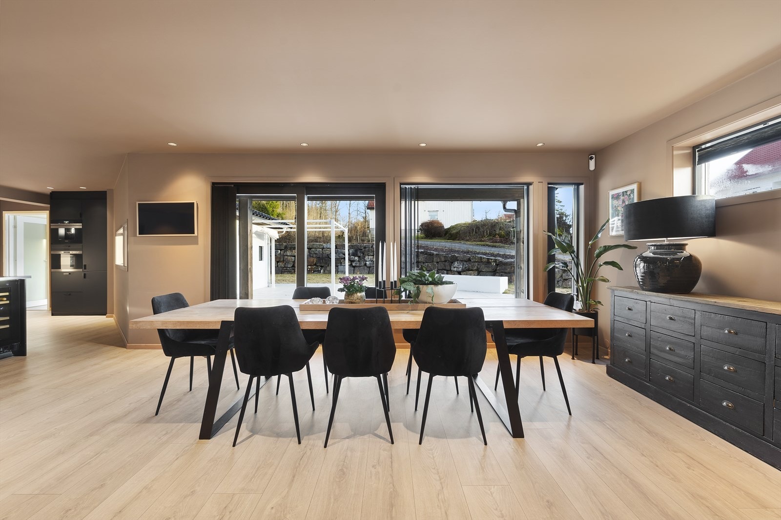 Fra spisestuen er det skyvedør i glass ut til den flislagte terrassen Galleribilde